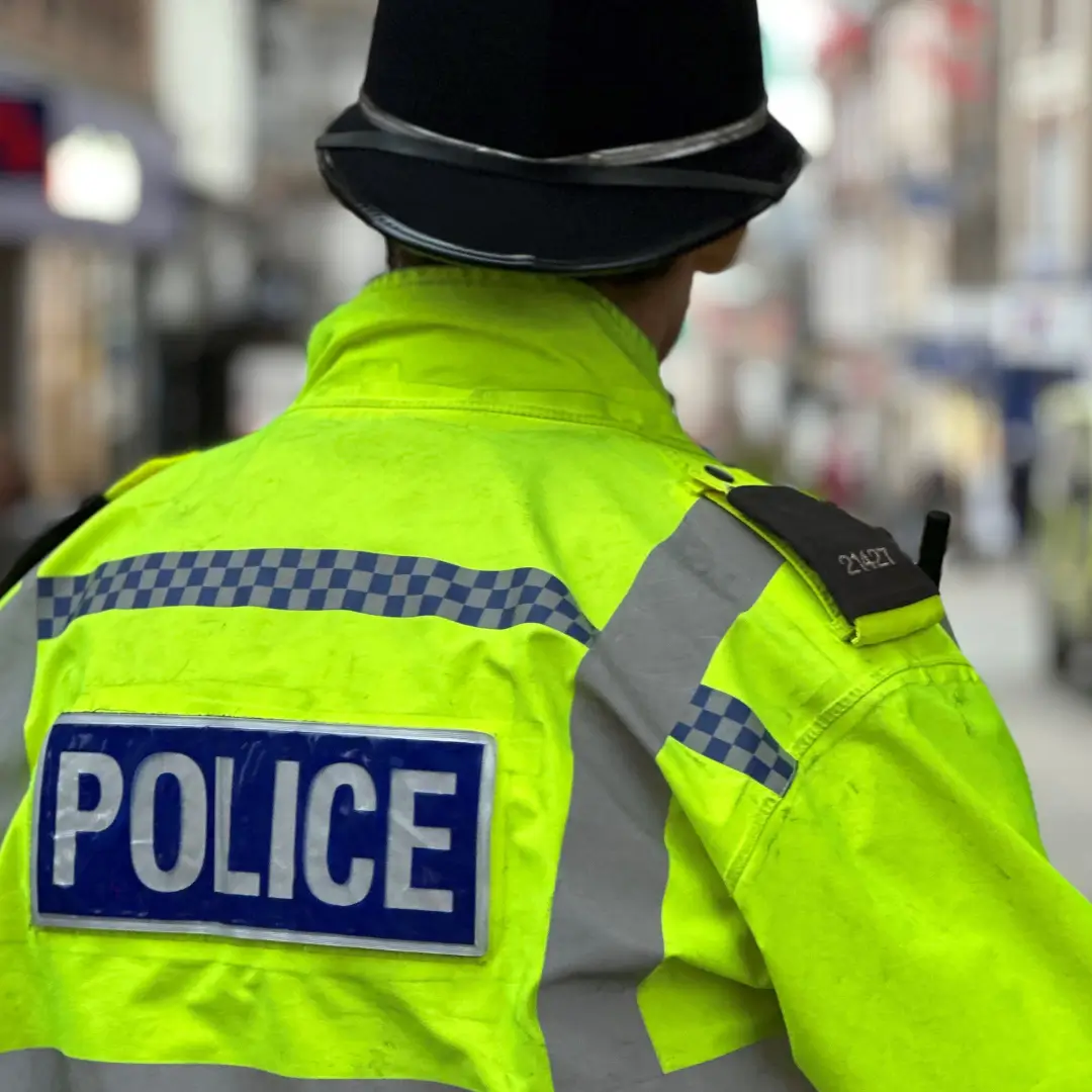 A police officer in a high visibility jacket and police hat